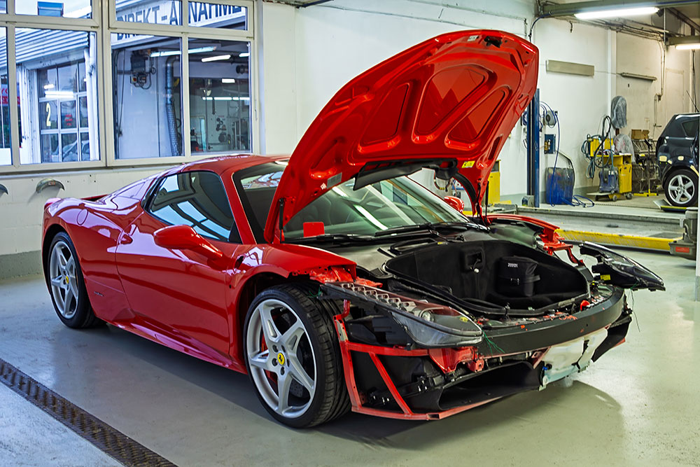 Damaged red sports car being assessed inside the Autohaus Bürkle workshop.